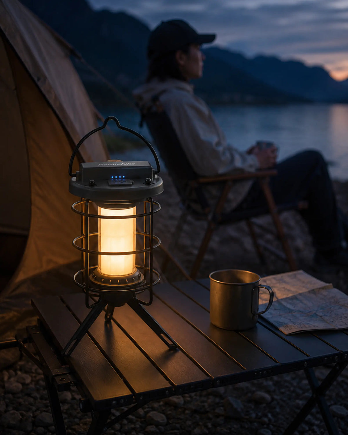 Naturehike Meteorite Black camping lantern beside a lakeside tent at twilight