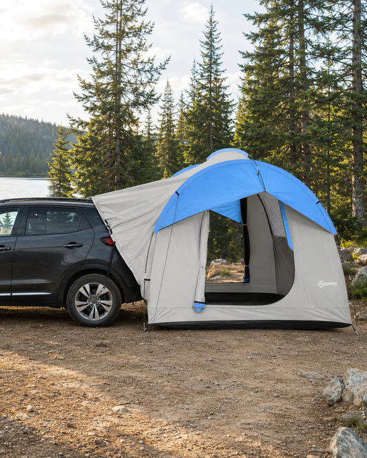 Grey and blue SUV tailgate tent connected to a CUV in forest camp