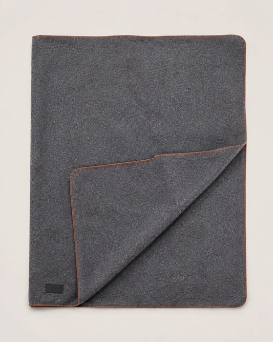 Reverse side of the light grey wool-blend camping blanket showing matching texture and orange edge stitching