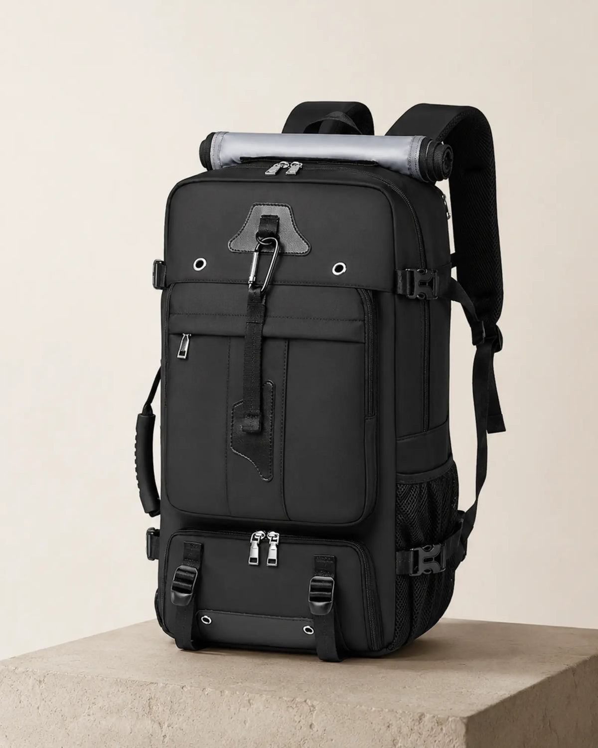 Black travel backpack photographed in a minimal studio editorial setting