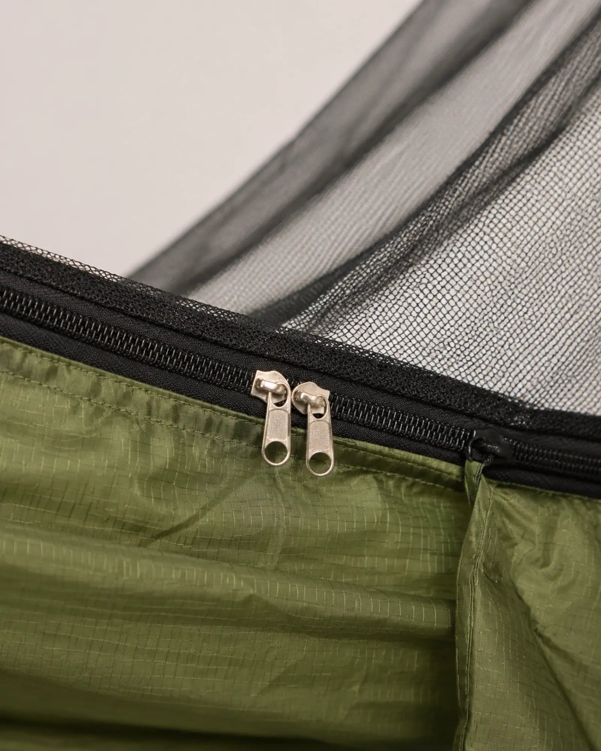 Close-up of the ArmyGreen ripstop seam, black zipper, and mesh binding