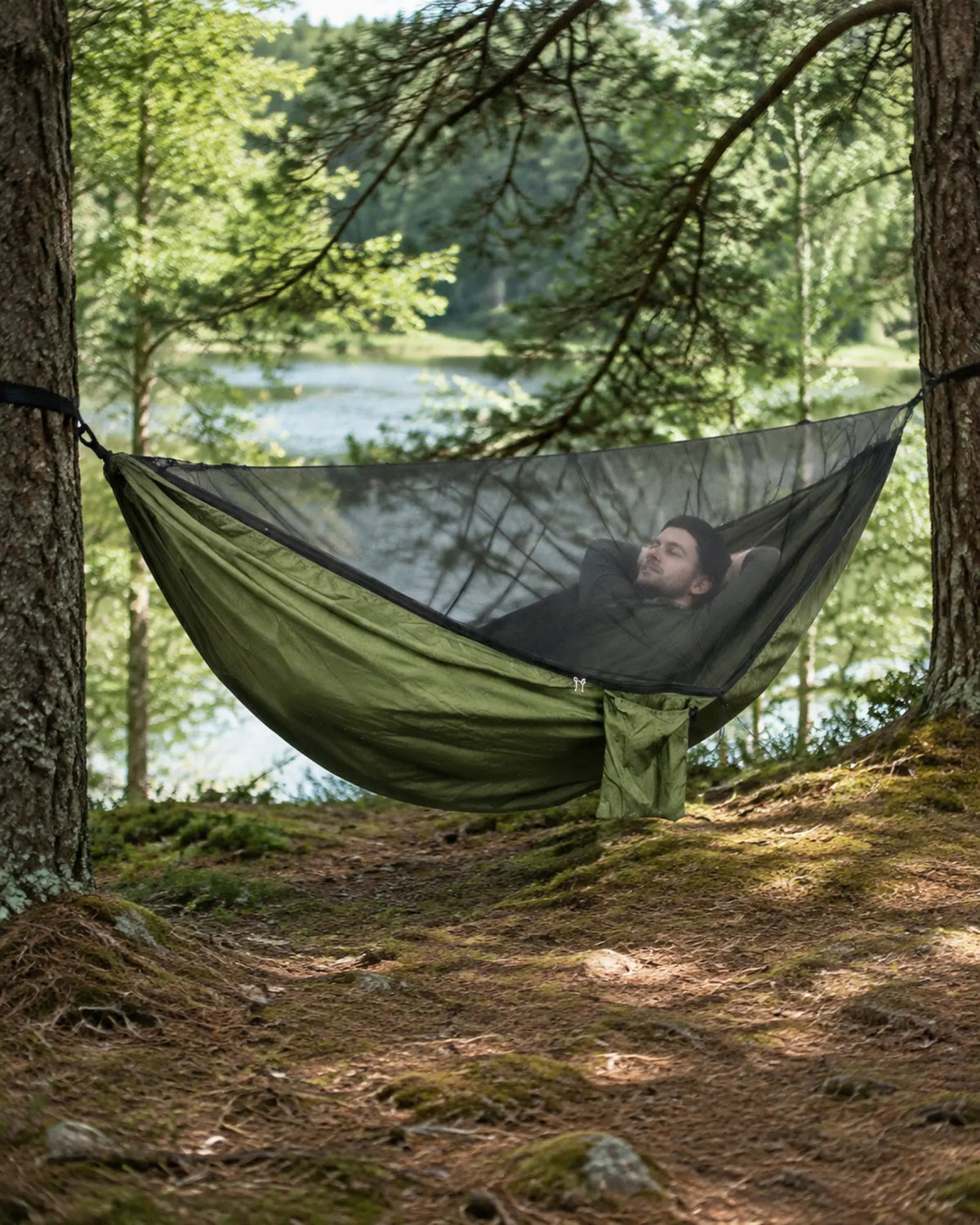 Traveler resting inside the ArmyGreen mosquito-net hammock in a forest