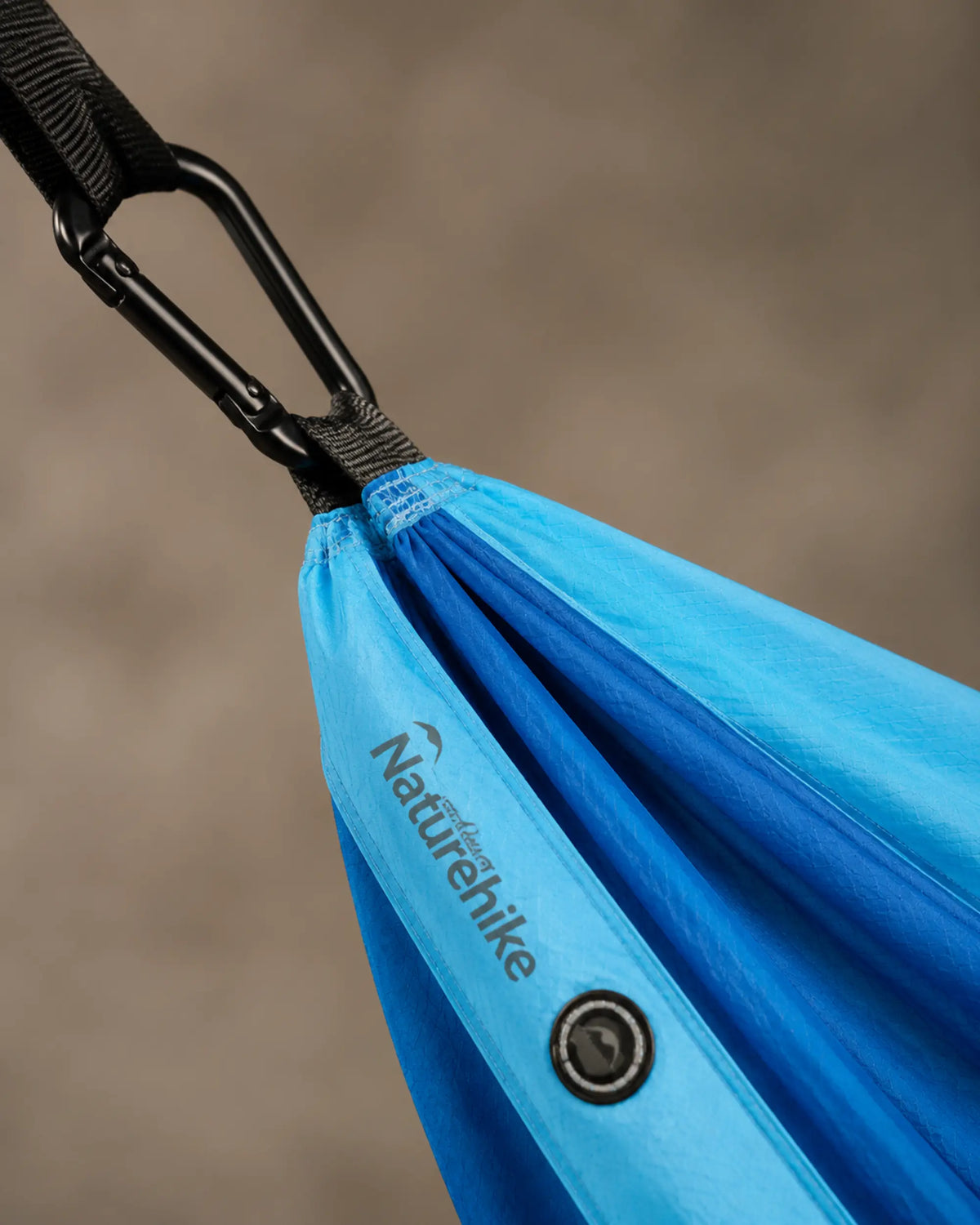 Close-up of black carabiner, suspension webbing and blue nylon hammock fabric