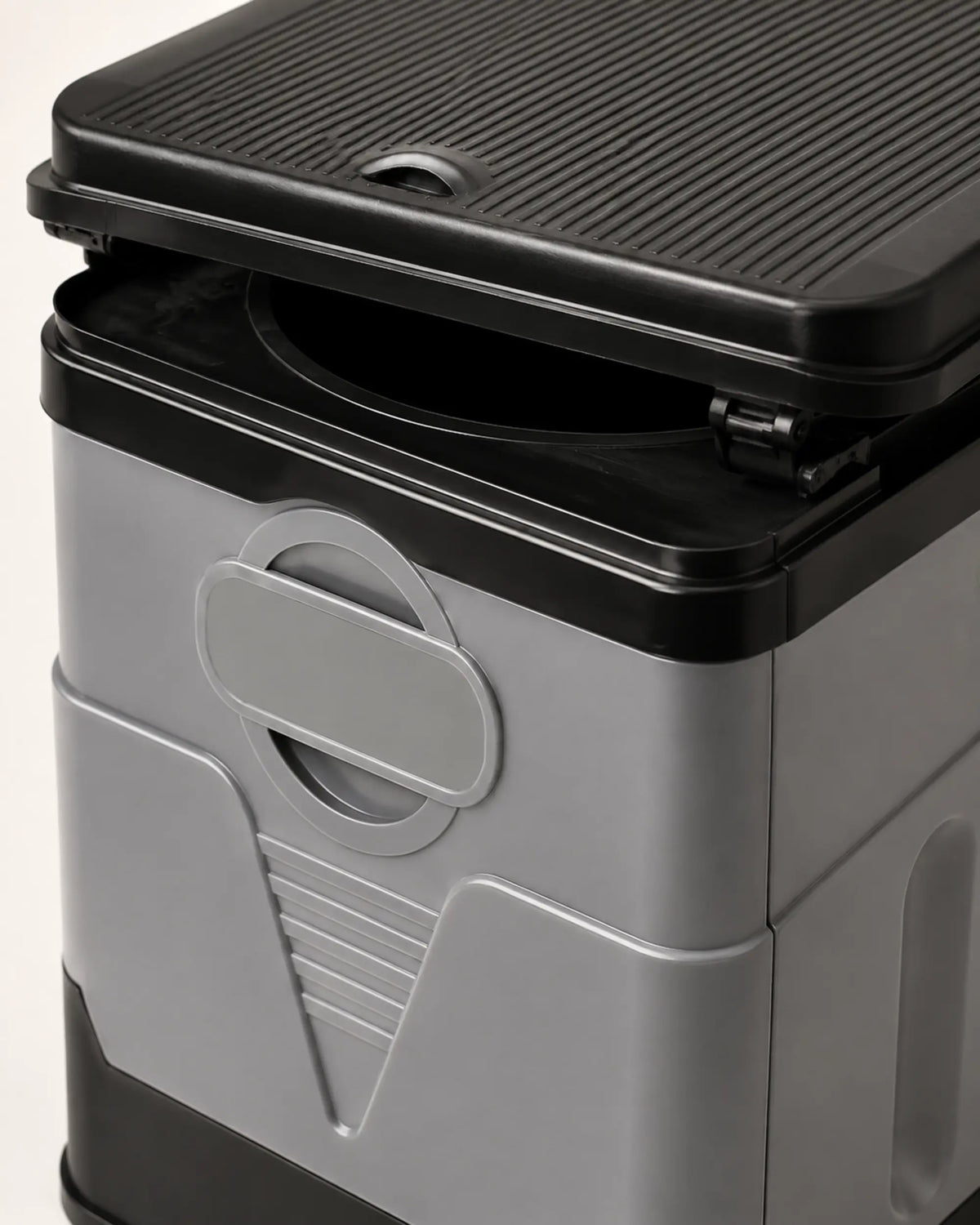 Close-up of the portable camping toilet integrated handle, locking panel seam, black rim and lid hinge