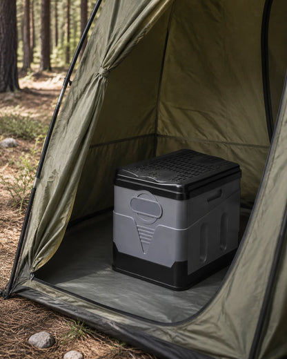 Grey foldable portable camping toilet with closed lid inside an outdoor privacy tent at a pine campsite