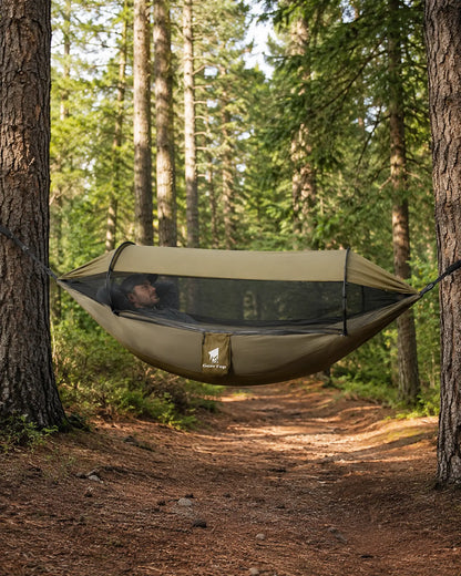 Hiker resting inside the GeerTop mosquito-net hammock on a forest trail