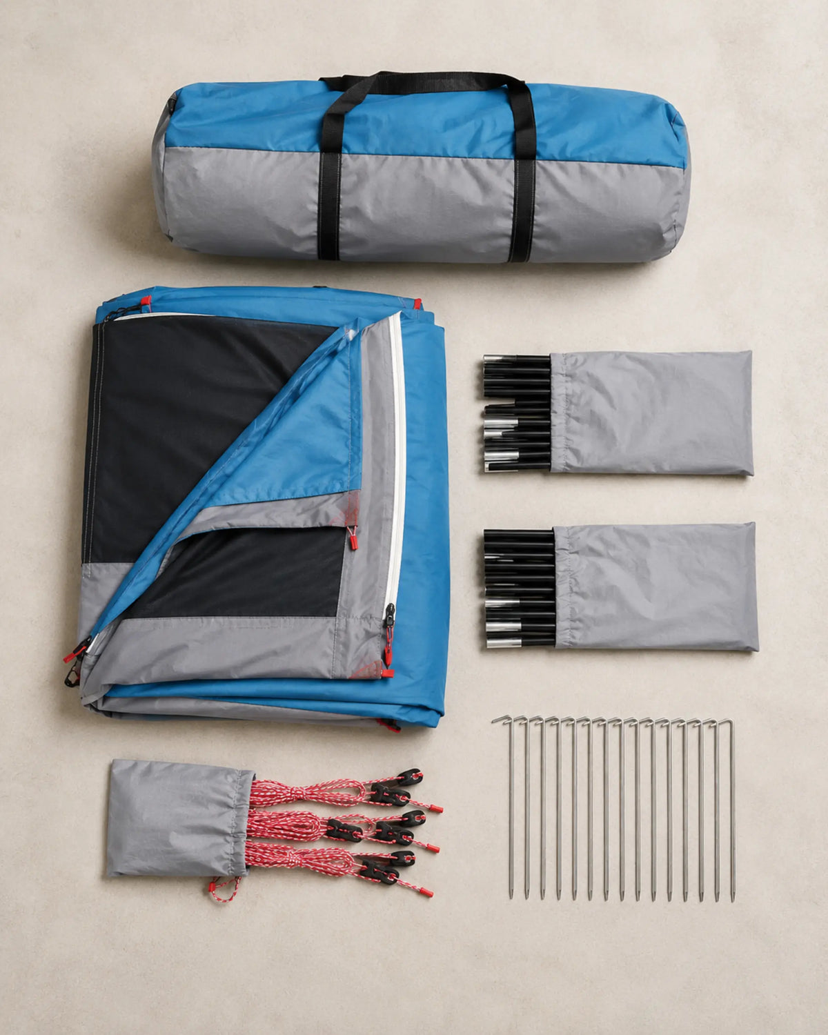 Blue family tent, carry bag, poles, guylines and stakes arranged flat