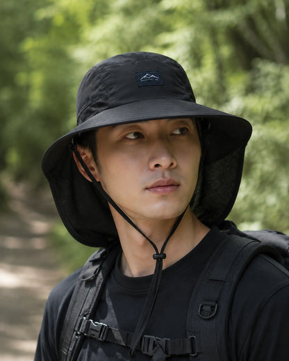 Hiker wearing black wide-brim sun hat with mesh neck protection on forest trail