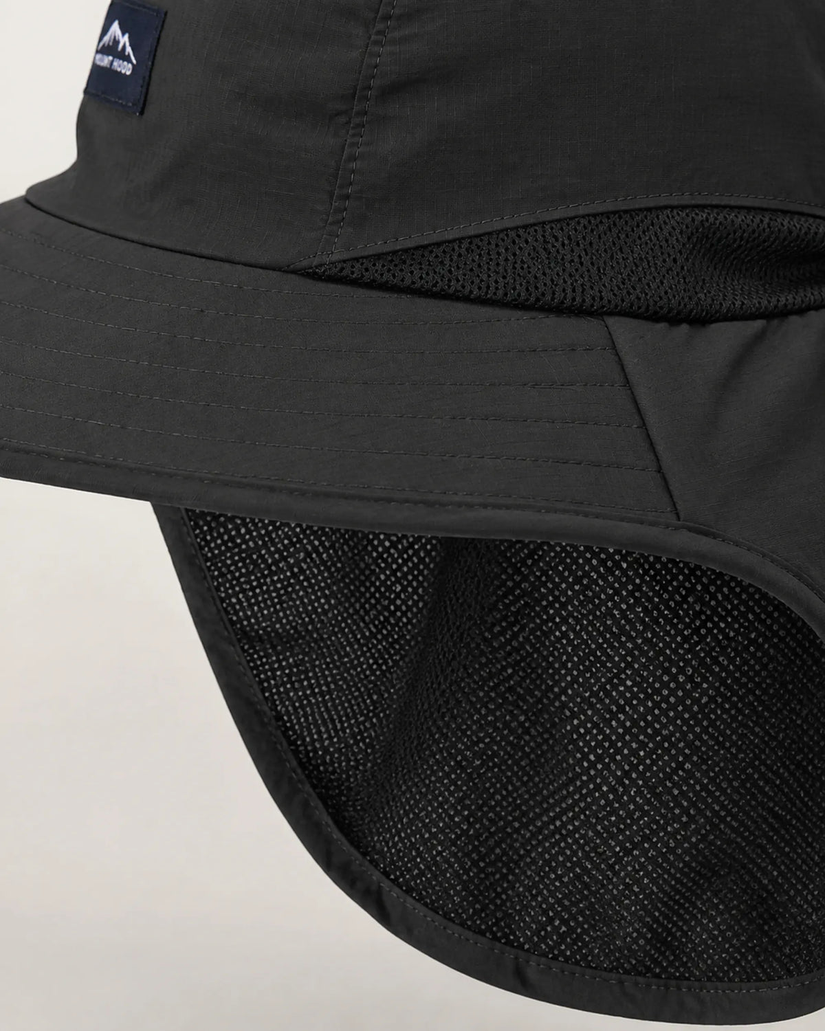 Macro detail of black sun hat ventilation mesh, stitching and bound neck flap