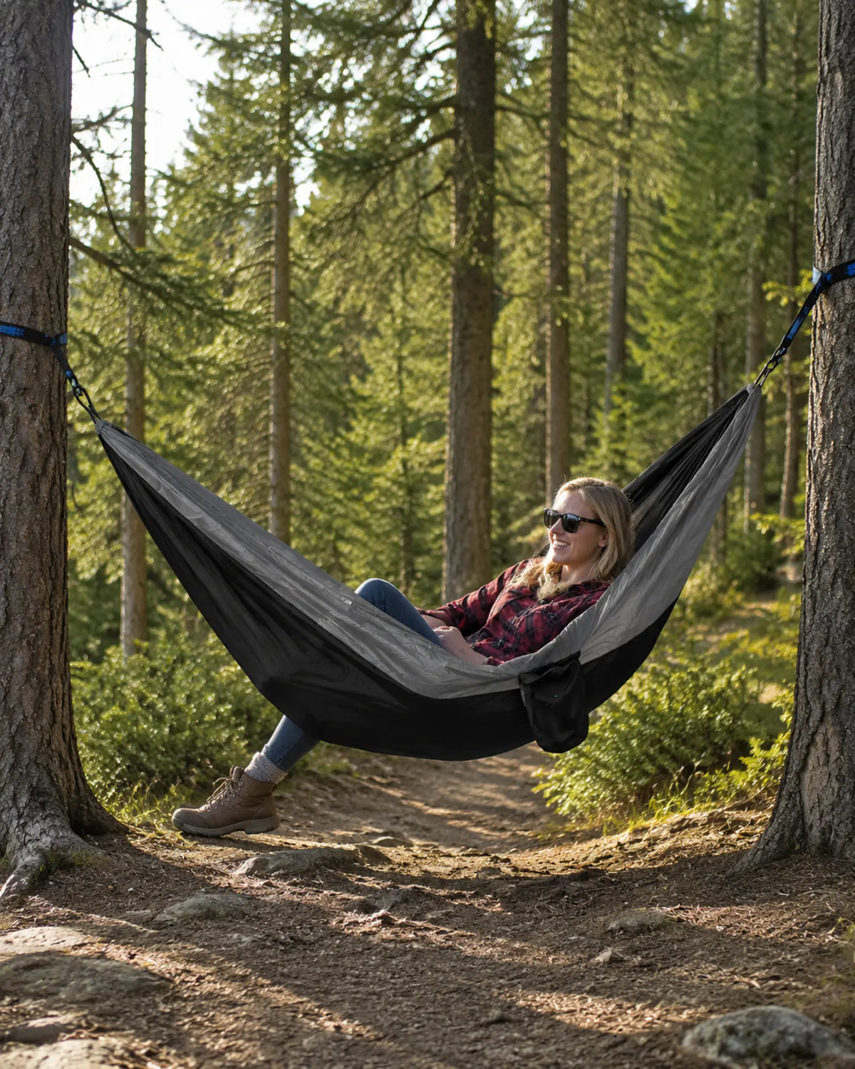 Hiker relaxing in the Black fight gray hammock on a forest trail