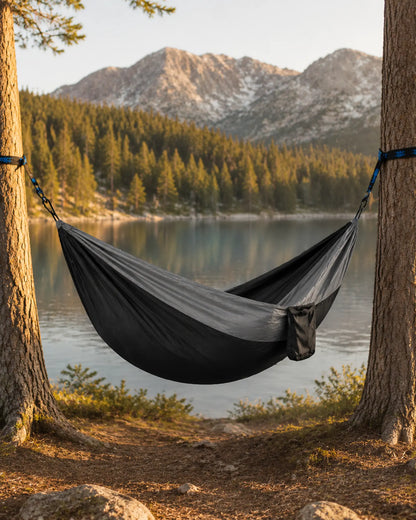 Empty Black fight gray camping hammock beside a mountain lake