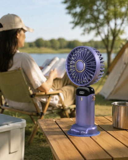 Blue portable fan cooling a reader at a warm lakeside campsite
