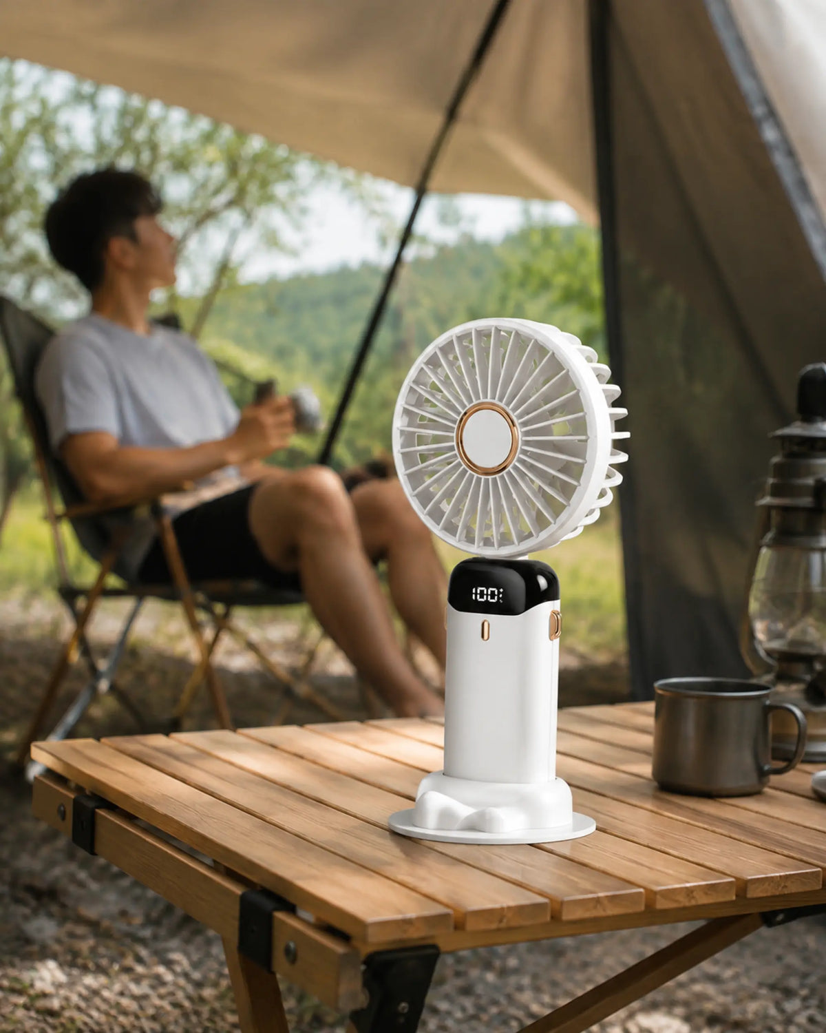 White portable desk fan cooling a camper beneath a shaded tent