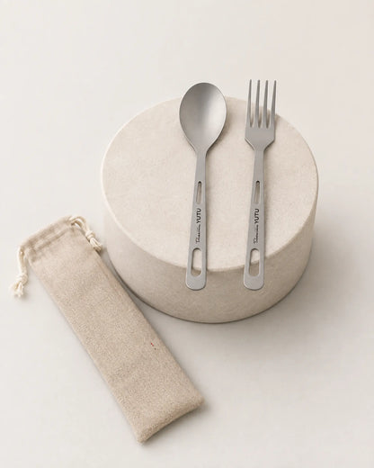 ARWE two-piece titanium cutlery displayed on a minimalist stone pedestal