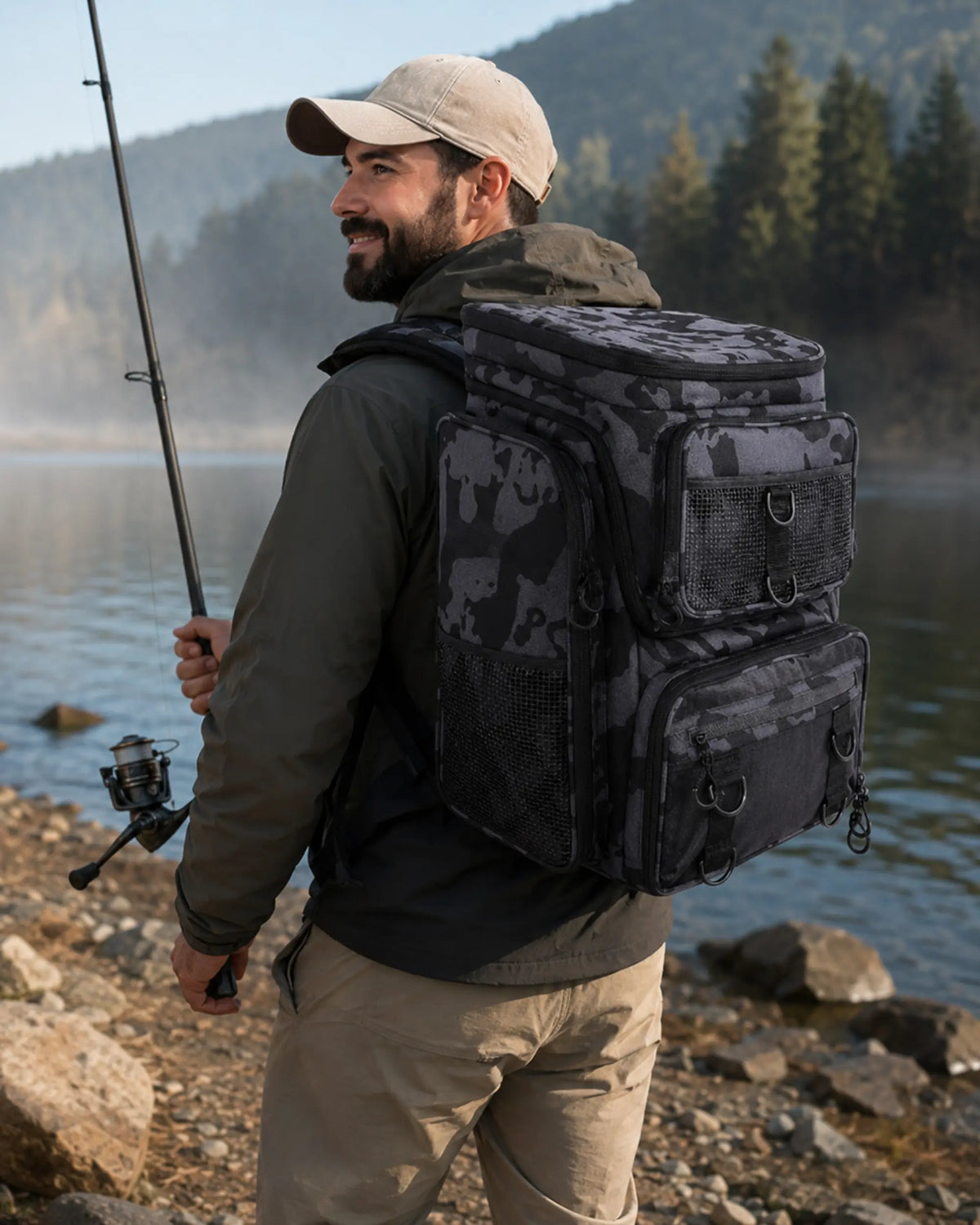 Angler wearing grey camouflage fishing tackle backpack at a mountain lake