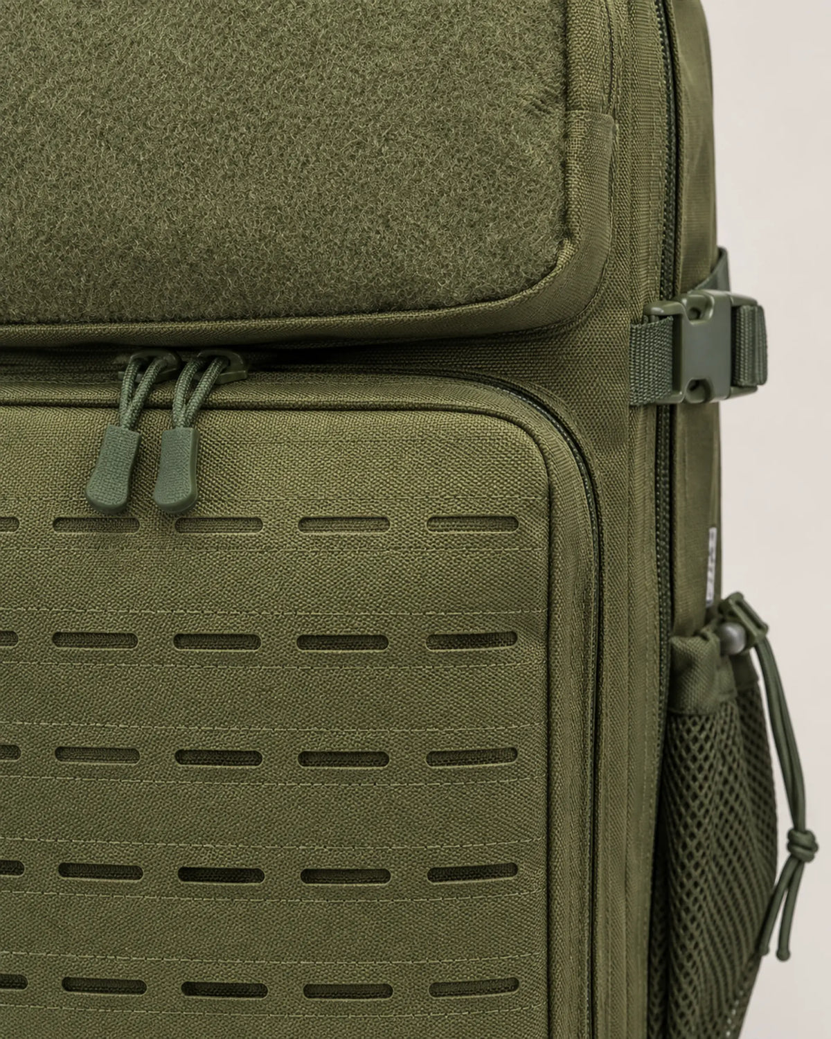 Close-up of army green tactical backpack velcro panel and laser-cut MOLLE slots