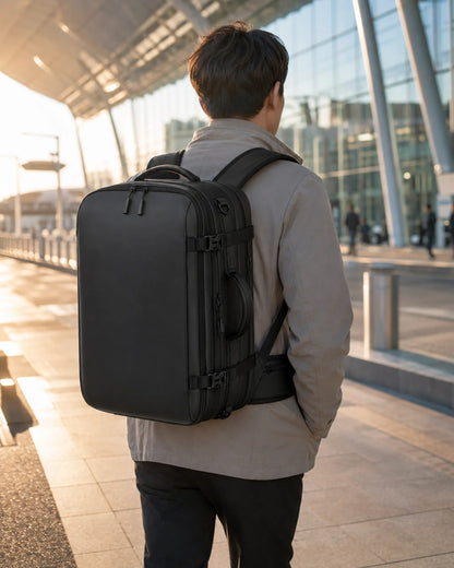 Black business travel backpack worn by a traveler outside a modern airport terminal