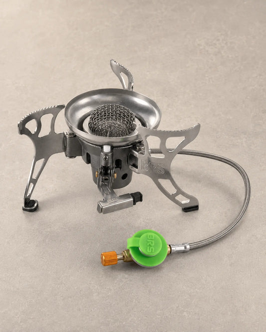 Left three-quarter view of the silver BRS-15 portable camping stove with folding supports and gas regulator