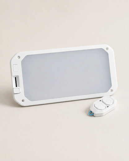 White dimmable RV ceiling light with two-button remote on a warm stone background