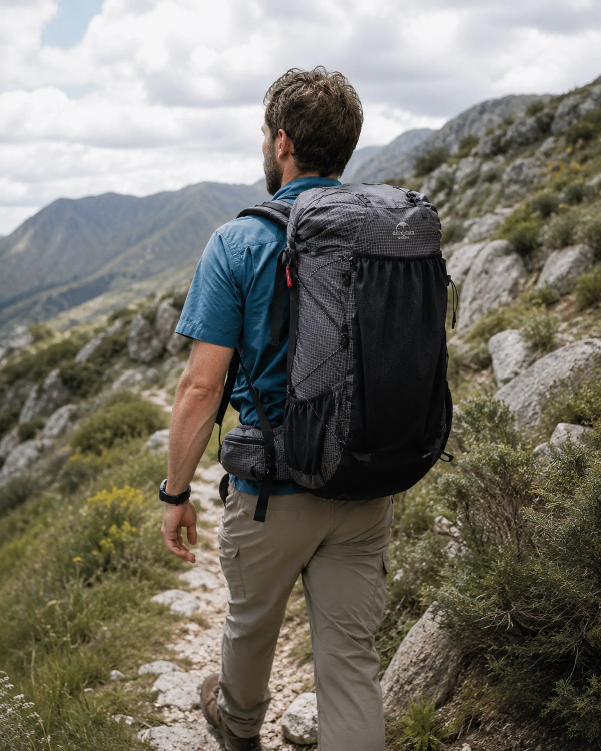 Day hiker carrying Naturehike 40L Black backpack through rocky highlands