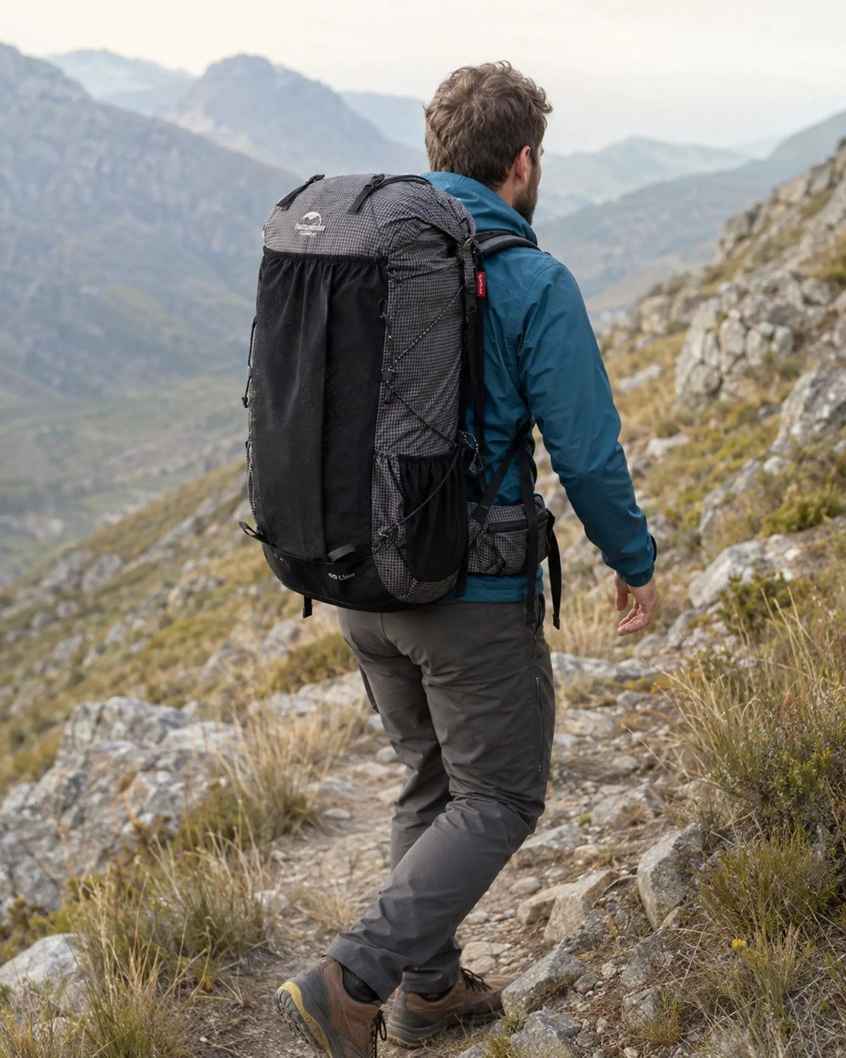 Hiker wearing Naturehike 60L Black backpack on a rocky alpine trail