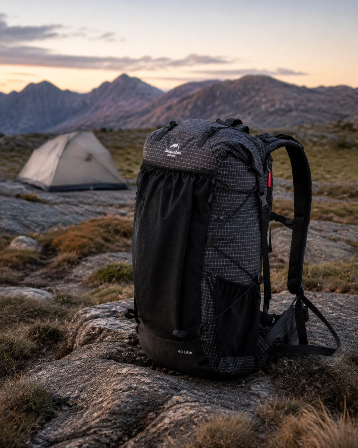 Naturehike 60L Upgraded Black backpack beside a quiet alpine campsite