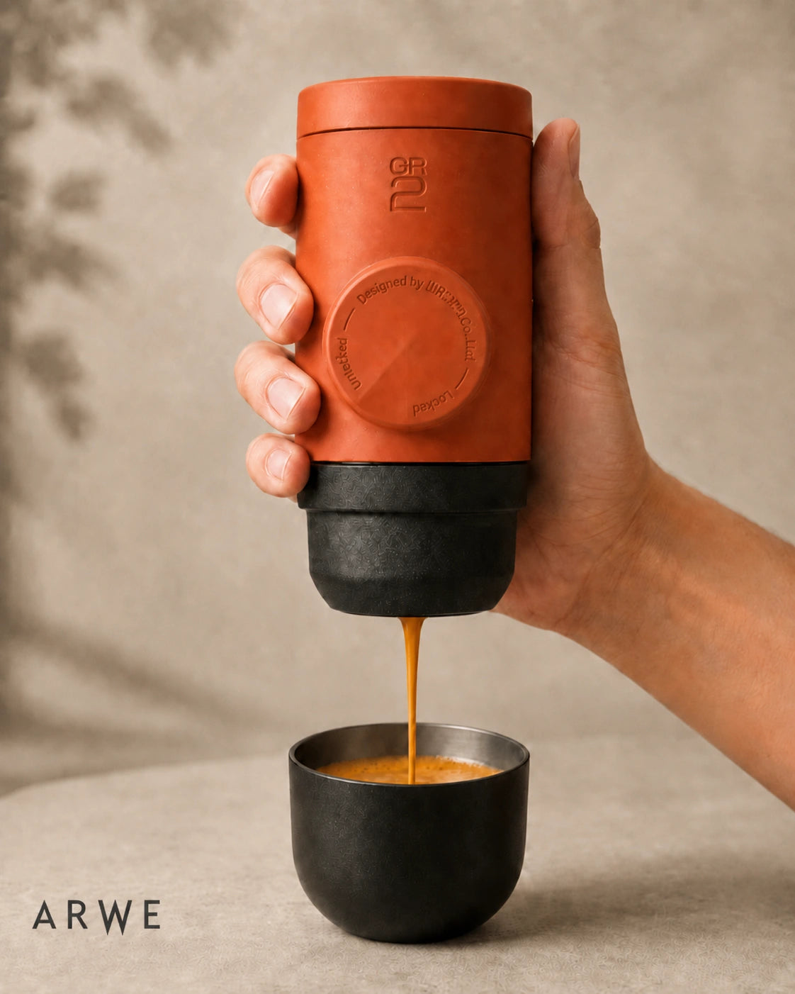 WACACO Minipresso GR2 in terracotta orange pouring espresso into a metal cup